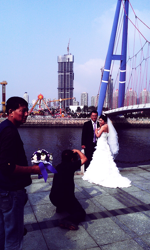 Chinese Wedding in Dalian: Bride and Groom are directed by photographers under Xinghai bridge